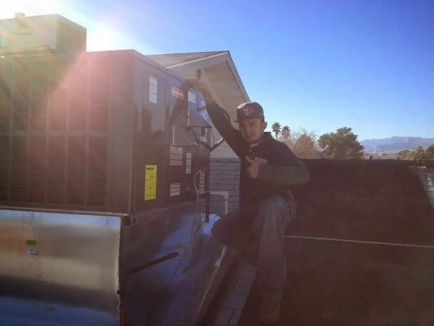 HVAC technician performing Air Duct Cleaning on a rooftop unit in Kingston